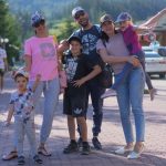 A joyful family of six spending quality time together in a scenic outdoor setting with mountains in the background.