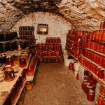 A cozy stone cellar filled with neatly arranged jars of preserves.